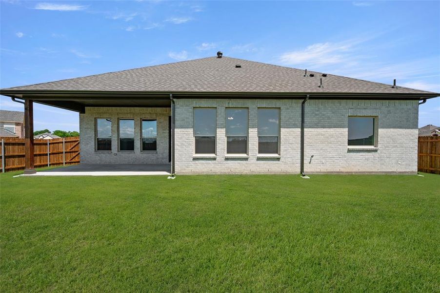 Rear view of property with a fenced backyard, a patio area, roof with shingles, and brick siding