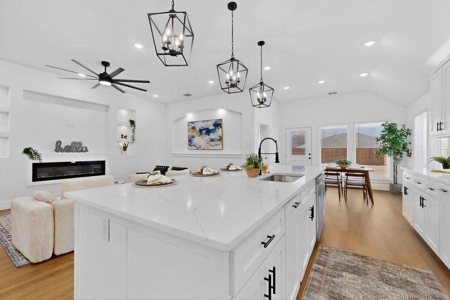 Kitchen with white cabinetry, ceiling fan, light wood-style flooring, light stone counters, and a spacious island Kitchen with white cabinetry, ceiling fan, light wood-style flooring, light stone counters, and a spacious island
