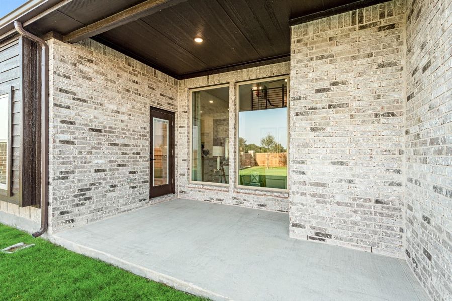 Covered back patio with concrete floor, light brick exterior, and large sliding glass door Covered back patio with concrete floor, light brick exterior, and large sliding glass door
