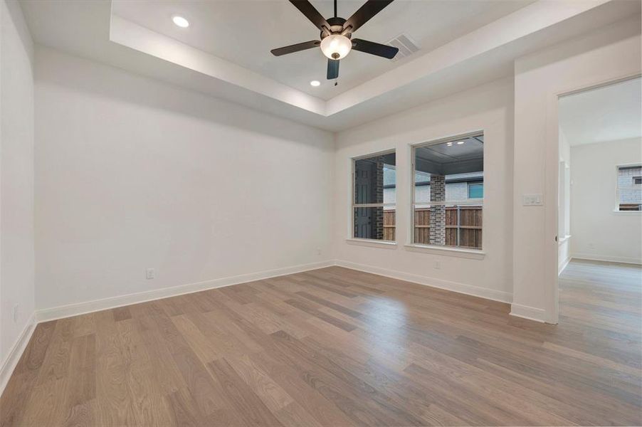 Room featuring light wood flooring, white walls, two windows, and a ceiling fan with integrated lighting