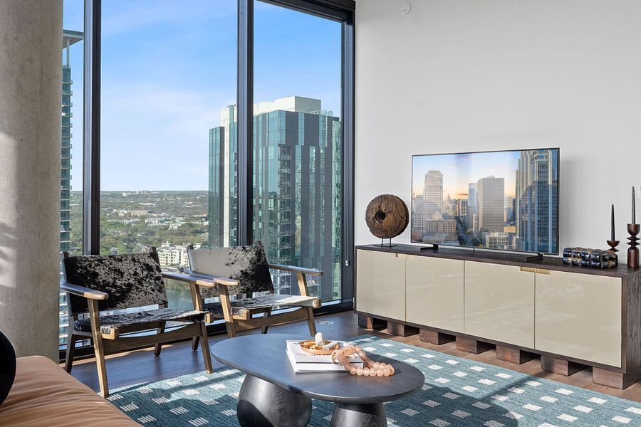Representative Photo. Open Concept living room with hardwood flooring, floor to ceiling windows, recessed lighting, ceiling fan, and a balcony off the living room with a South East view