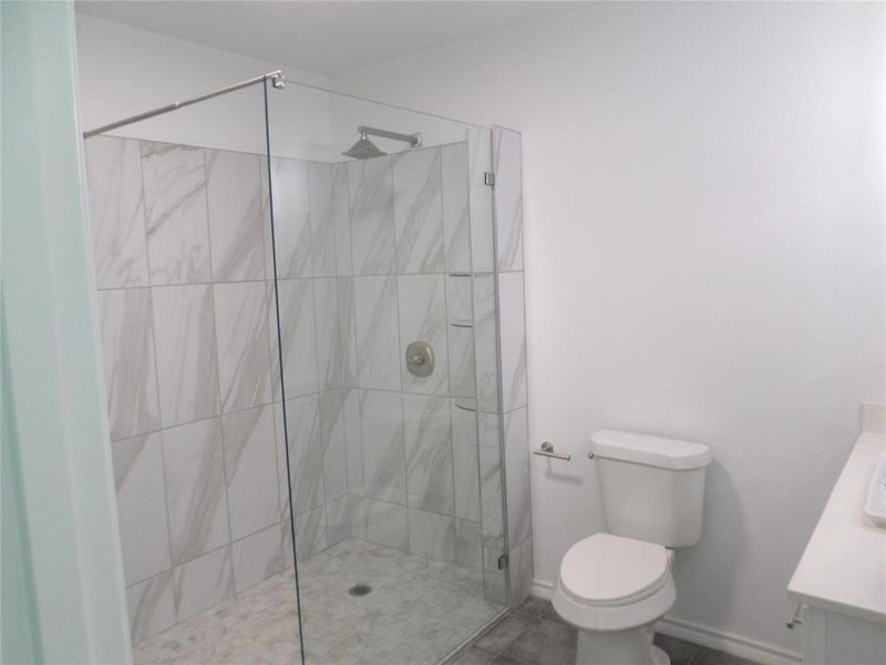 Glass-enclosed shower with large format tile surround and rainfall showerhead