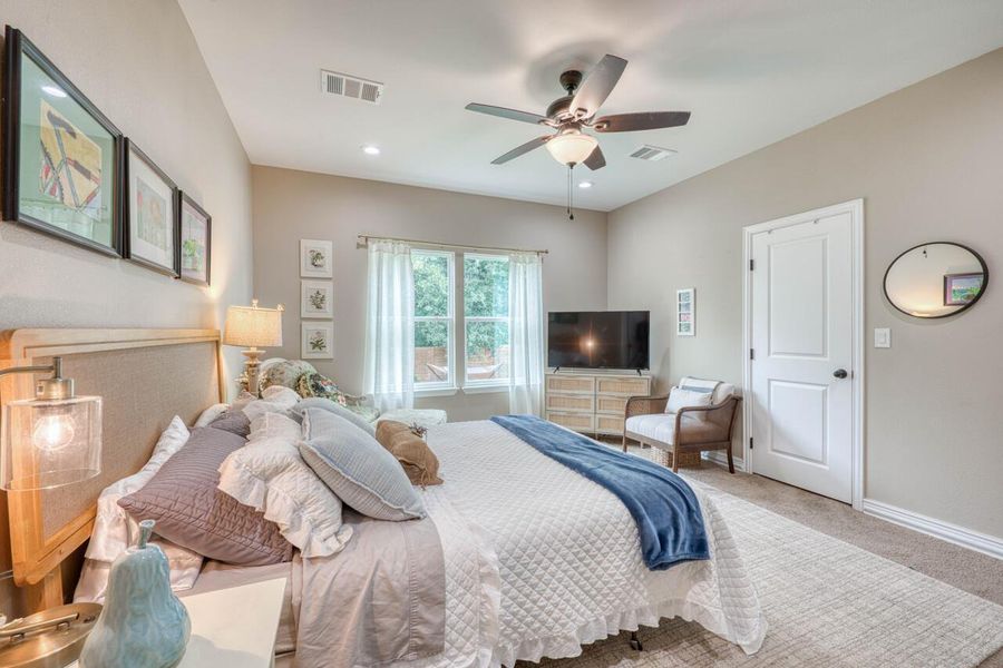 Neutral-toned bedroom featuring a vaulted ceiling with a ceiling fan