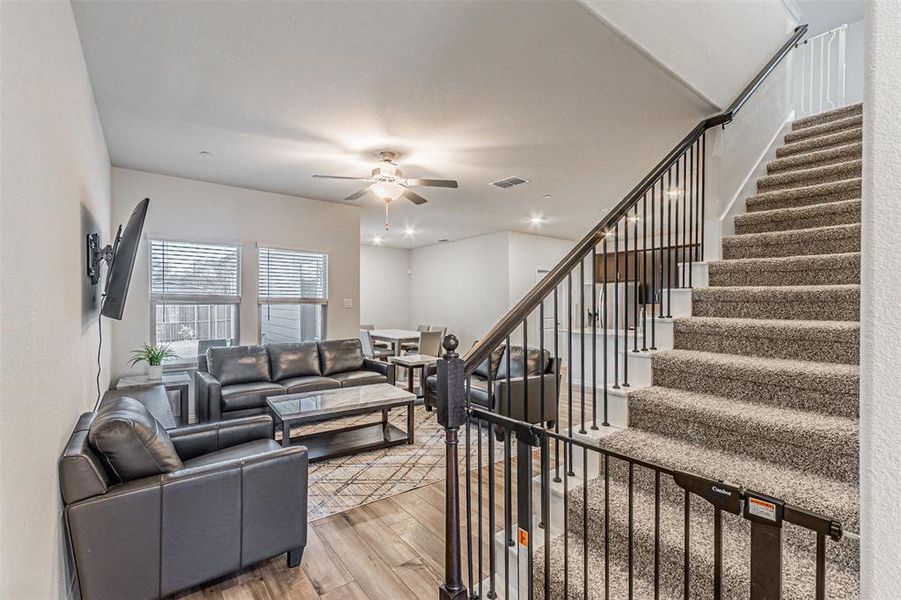 Living room with stairway, visible vents, recessed lighting, ceiling fan, and light wood-type flooring