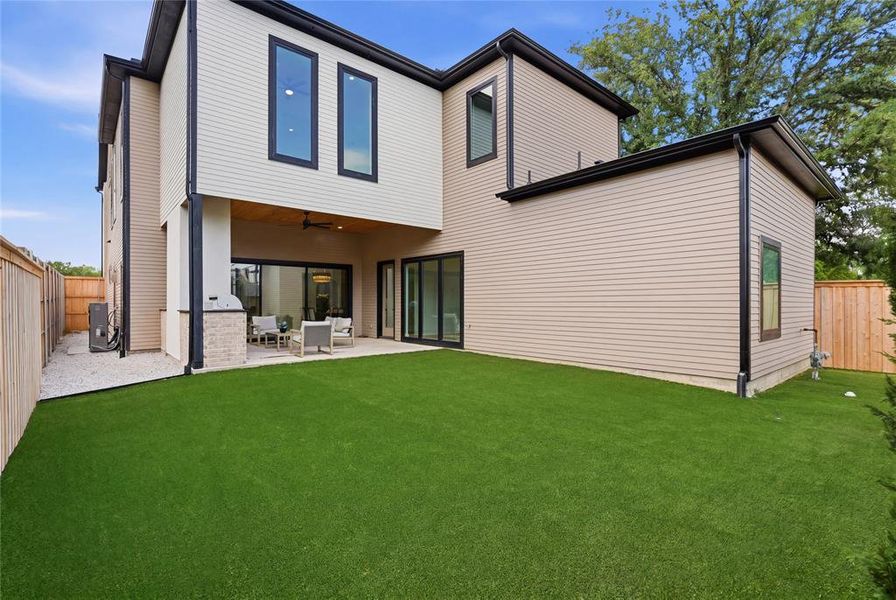 Spacious rear yard featuring an artificial turf lawn and a concrete patio Spacious rear yard featuring an artificial turf lawn and a concrete patio