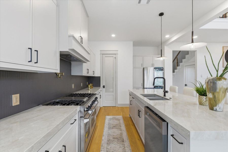 Porcelain countertops, custom inset cabinetry, a pot filler, 48-inch gas range, and neutral finishes give the home an elevated yet warm and inviting feel.