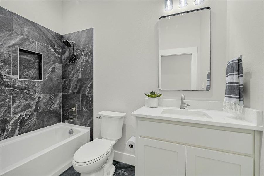 Full bathroom featuring tiled shower / bath combo, vanity, and toilet