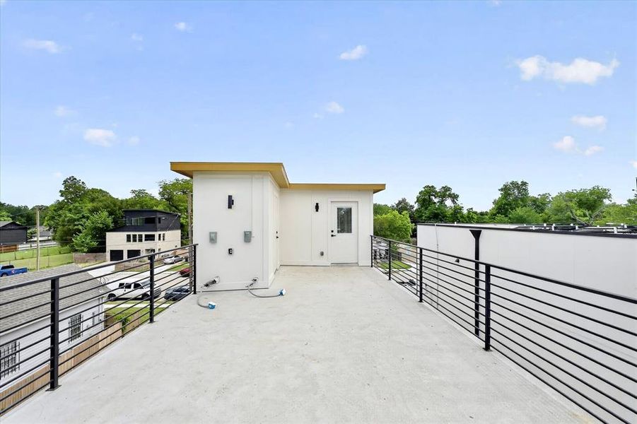 Expansive rooftop deck featuring a concrete surface and contemporary black metal railings
