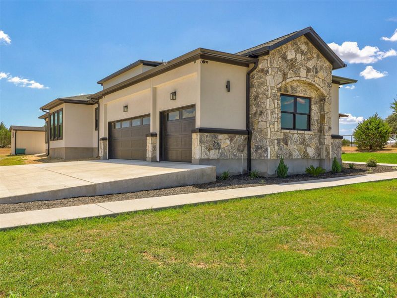 Textured stone accents and smooth stucco define this modern exterior with a spacious concrete driveway.