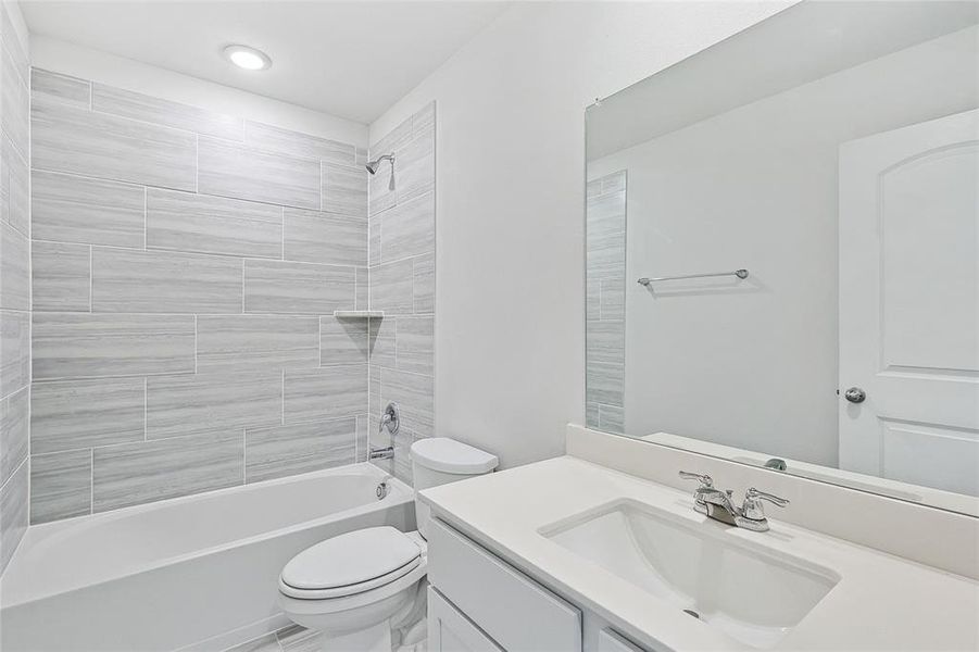 Full bathroom featuring tiled shower / bath, vanity, and toilet