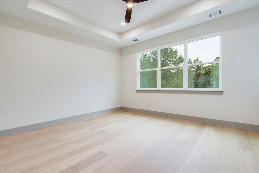 Spare room with light wood-style flooring, a tray ceiling, ceiling fan, and recessed lighting