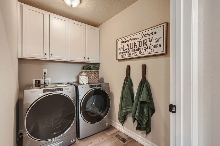 A laundry room with white cabinets.