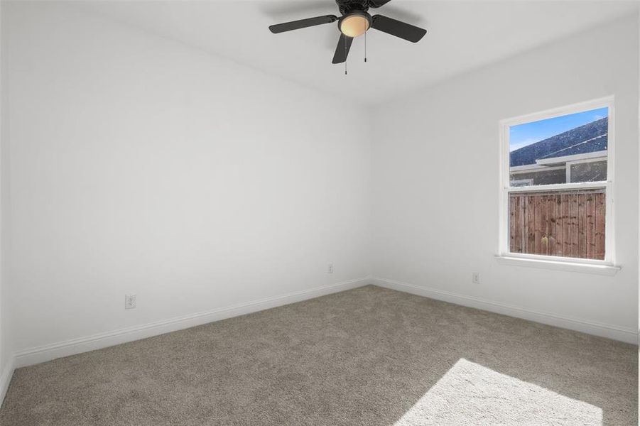 Carpeted empty room with plenty of natural light and ceiling fan