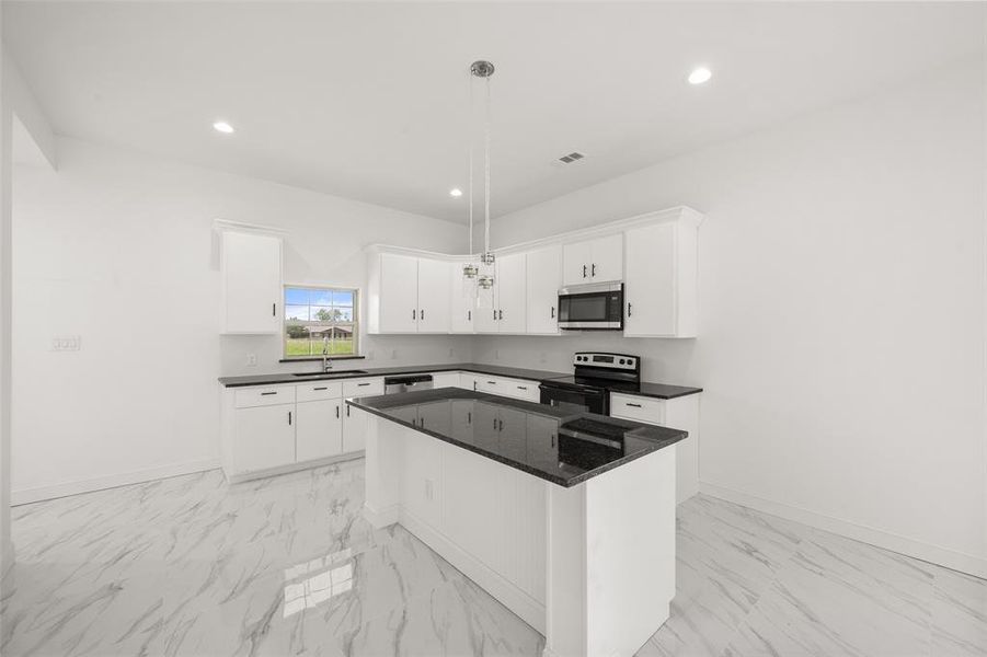 Kitchen with stainless steel appliances, light marble finish flooring, dark countertops, white cabinetry, and recessed lighting Kitchen with stainless steel appliances, light marble finish flooring, dark countertops, white cabinetry, and recessed lighting