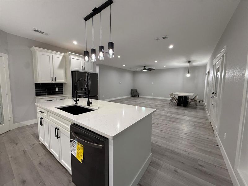Kitchen featuring hanging light fixtures, white cabinetry, black appliances, open floor plan, and recessed lighting