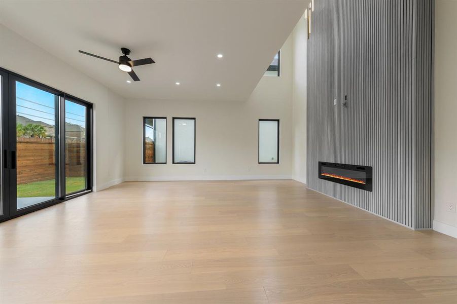 Family room featuring a glass covered fireplace, light wood-style flooring, a ceiling fan, and recessed lighting