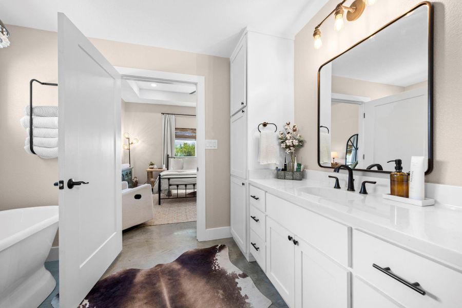 Full bath featuring concrete flooring, vanity, a freestanding tub, and a raised ceiling