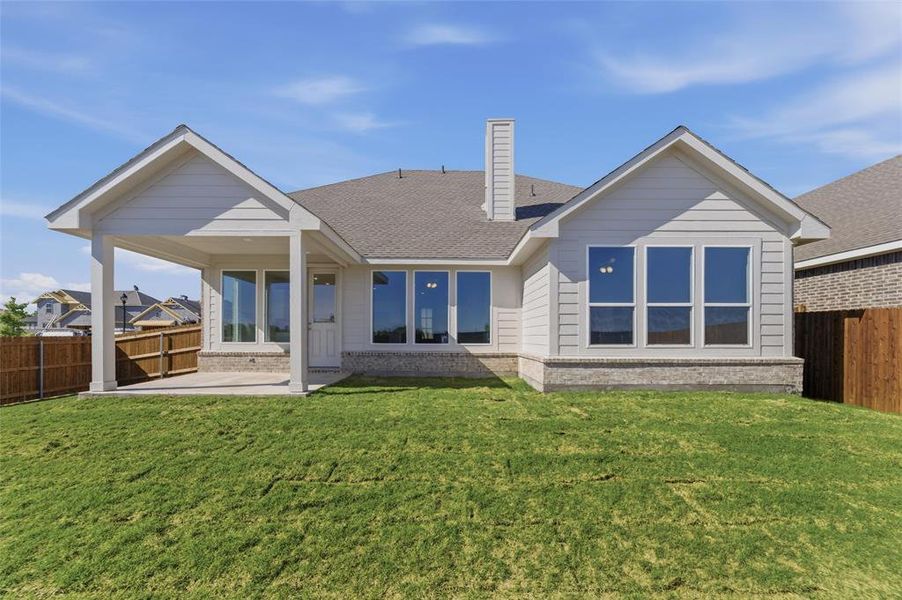 Rear view of house with a fenced backyard, a patio, a chimney, brick siding, and a shingled roof