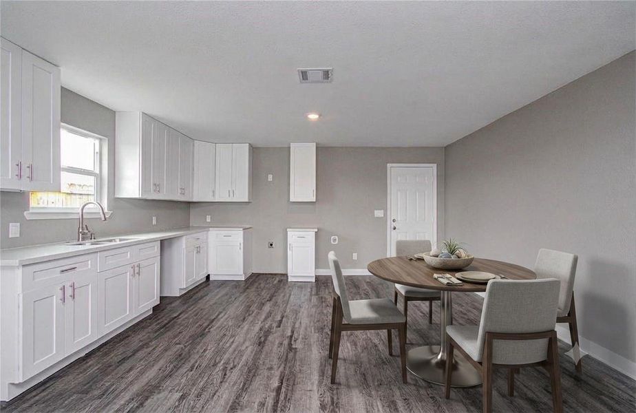 Bright kitchen featuring white cabinetry, generous counter space, and a window above the sink. (Virtually Staged)