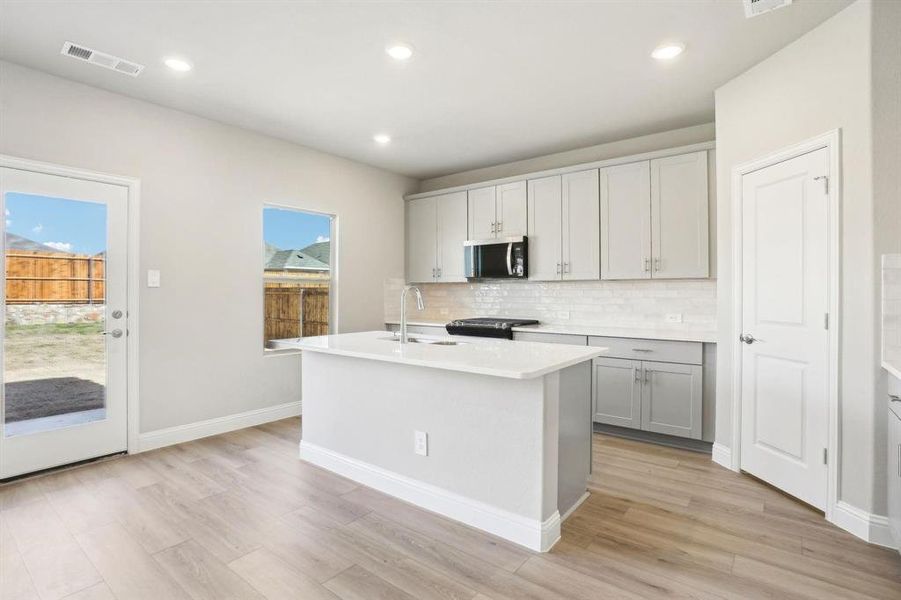 Kitchen featuring decorative backsplash, an island with sink, plenty of natural light, light wood-style flooring, and recessed lighting Kitchen featuring decorative backsplash, an island with sink, plenty of natural light, light wood-style flooring, and recessed lighting