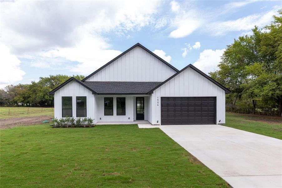 Modern farmhouse style home with a garage and a front yard