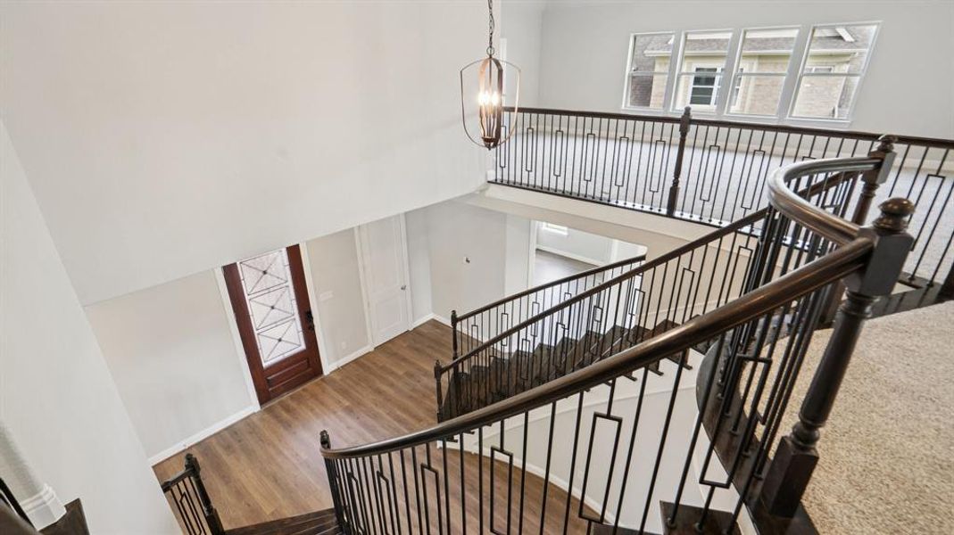 Stairway with a towering ceiling, wood finished floors, and a chandelier Stairway with a towering ceiling, wood finished floors, and a chandelier