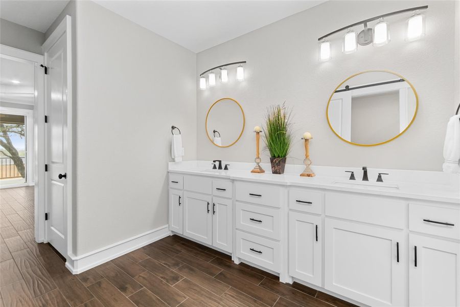 Bathroom featuring double vanity, wood tiled floors, and baseboards Bathroom featuring double vanity, wood tiled floors, and baseboards