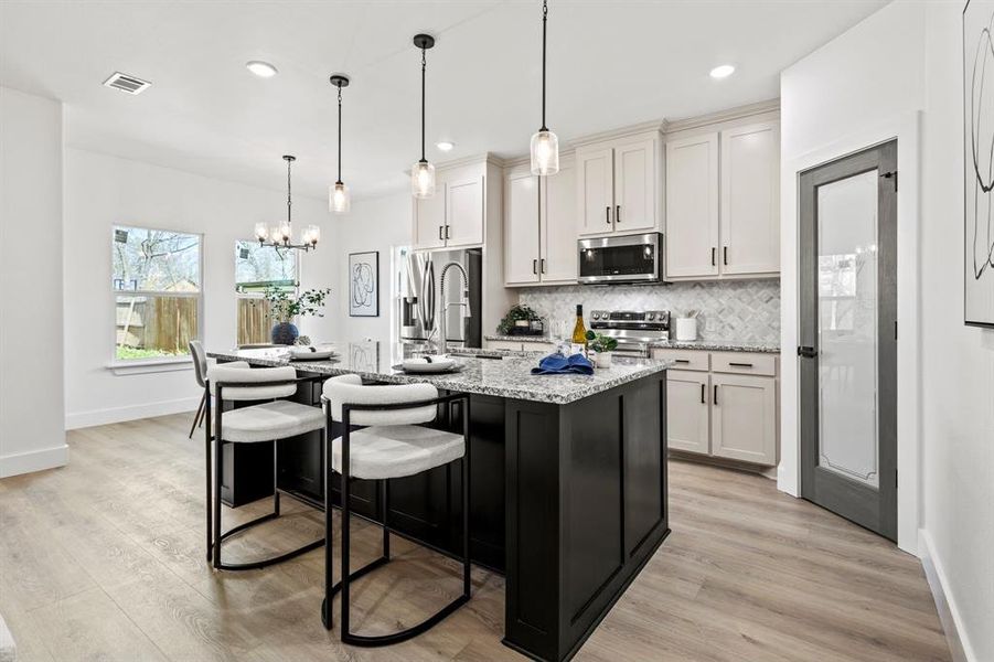 Kitchen featuring visible vents, a center island with sink, a kitchen breakfast bar, stainless steel appliances, and decorative backsplash