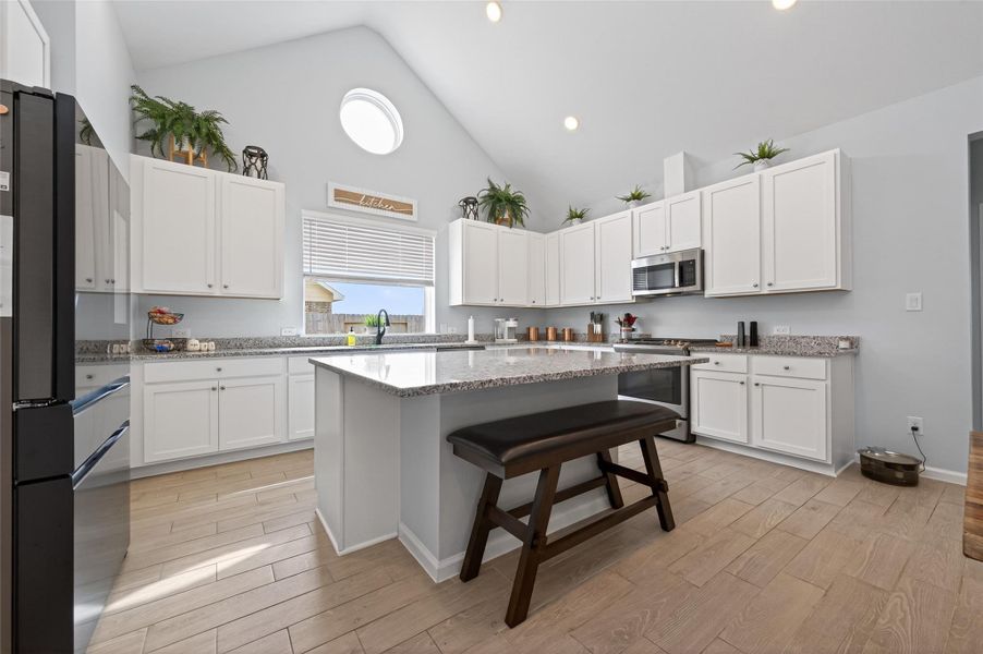 Open kitchen layout featuring a large island with a breakfast bar, flooded with natural light