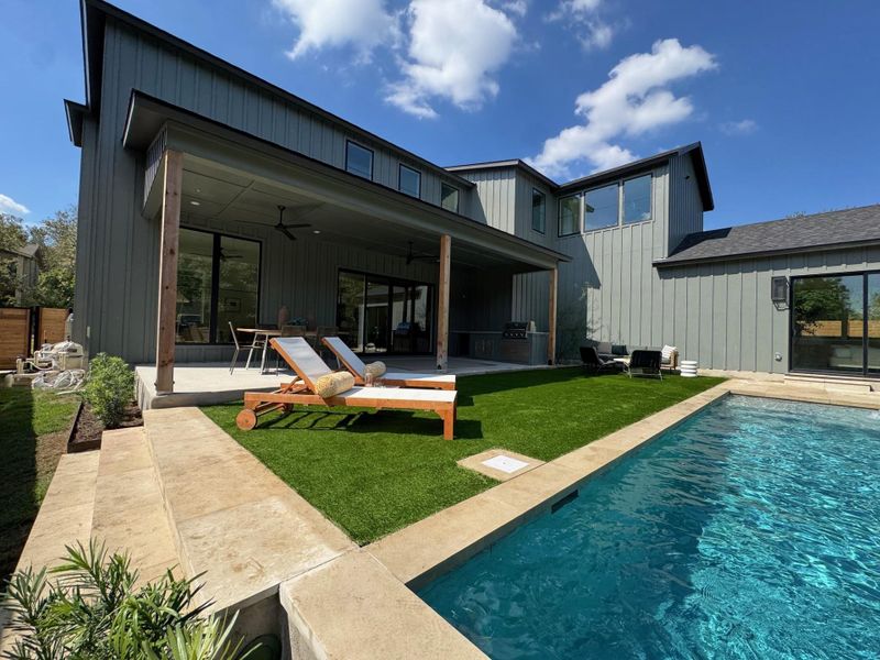 Rear view of house featuring ceiling fan, a patio area, a yard, an outdoor pool, and board and batten siding Rear view of house featuring ceiling fan, a patio area, a yard, an outdoor pool, and board and batten siding