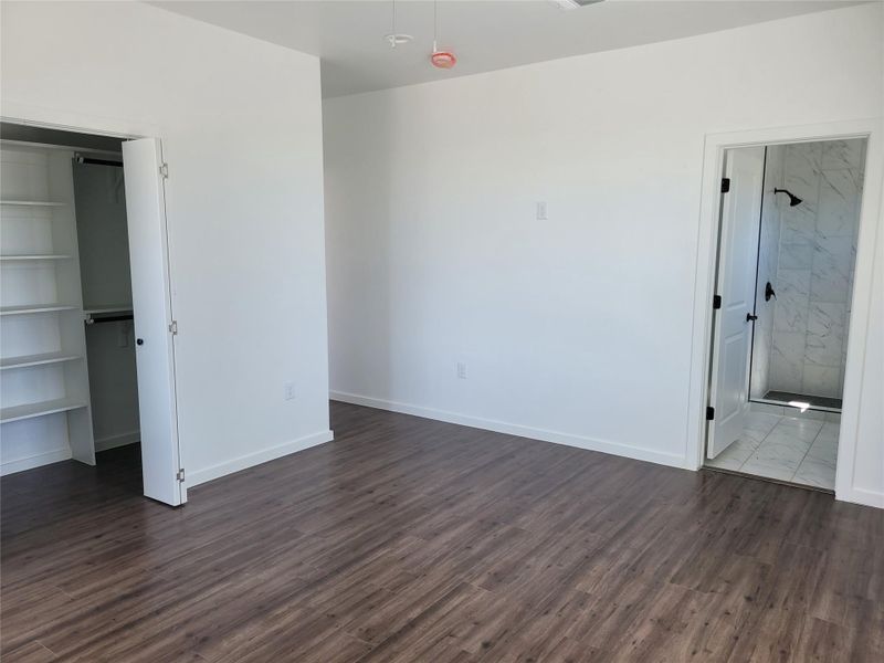 Ample floor space and rich flooring define this versatile room, featuring an adjoining walk-in closet and a shower bathroom.