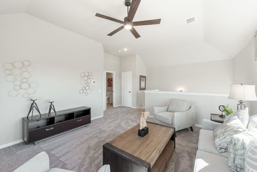 Open loft living area with vaulted ceiling, ceiling fan, gray carpet, and neutral furniture