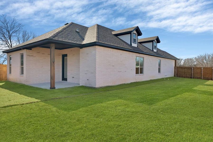 Rear view of house featuring brick siding, a patio, and a shingled roof