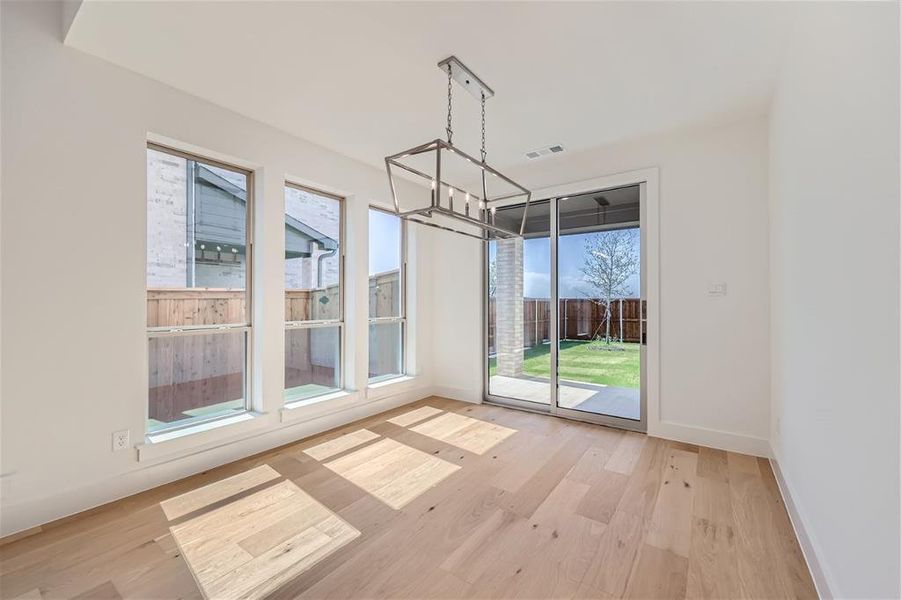 Unfurnished dining area featuring light hardwood / wood-style floors, a notable chandelier, and a wealth of natural light