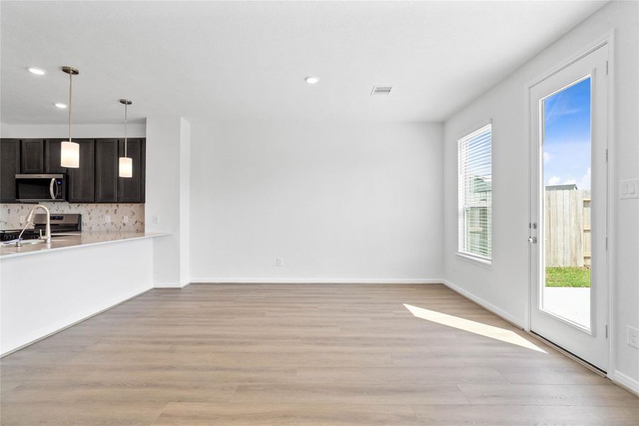 Start your day with a warm cup of coffee and quality time in this charming dining area! Highlights include a large window with blinds, custom neutral paint, vinyl plank flooring, recessed lighting, high ceilings, and a convenient door leading to the rear patio and backyard.