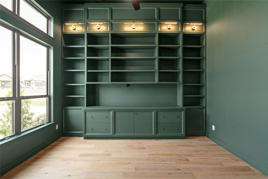 Elegant study with custom built-in shelving, color drenched room, and large windows for natural light, offering a perfect balance of sophistication and functionality.