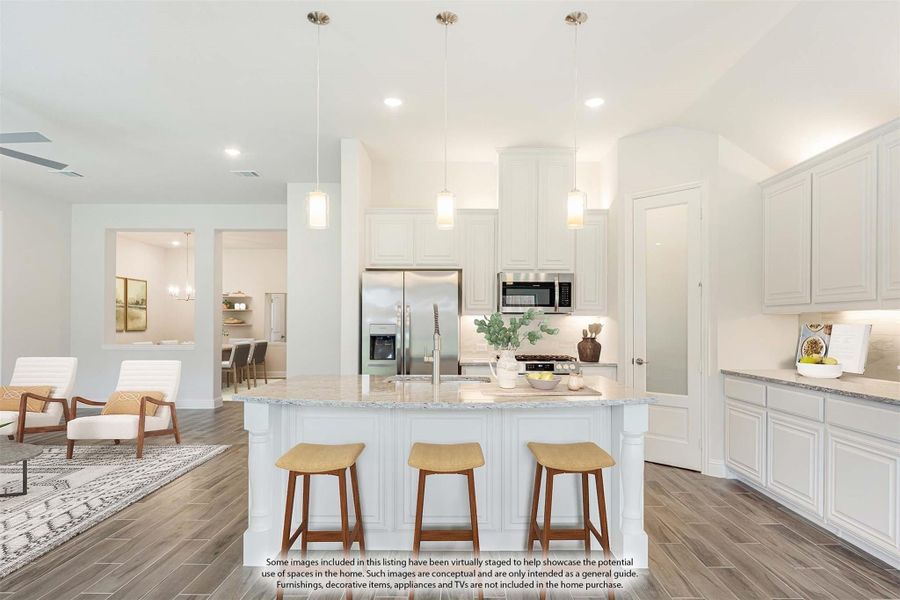 Open kitchen with white cabinets, large island with three bar stools, pendant lights, and stainless steel appliances