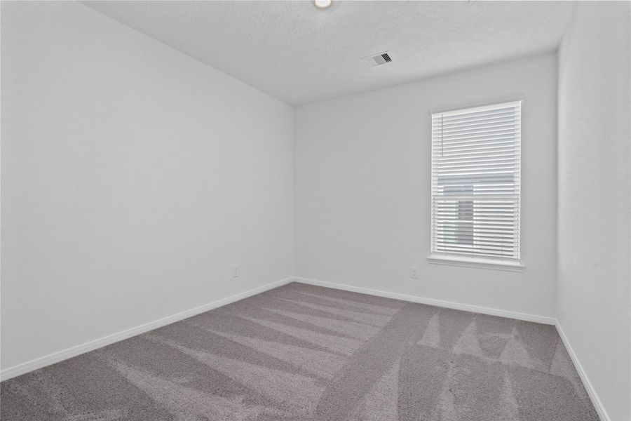 The Den is a versatile and additional living space that can be used as a home office, hobby or play room. It features carpet flooring, high ceilings, recessed lighting, neutral paint, and a large window with privacy blinds.