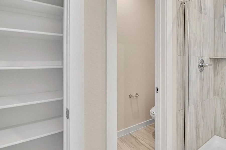Full bath with a stall shower, a spacious closet, and wood finished floors Full bath with a stall shower, a spacious closet, and wood finished floors