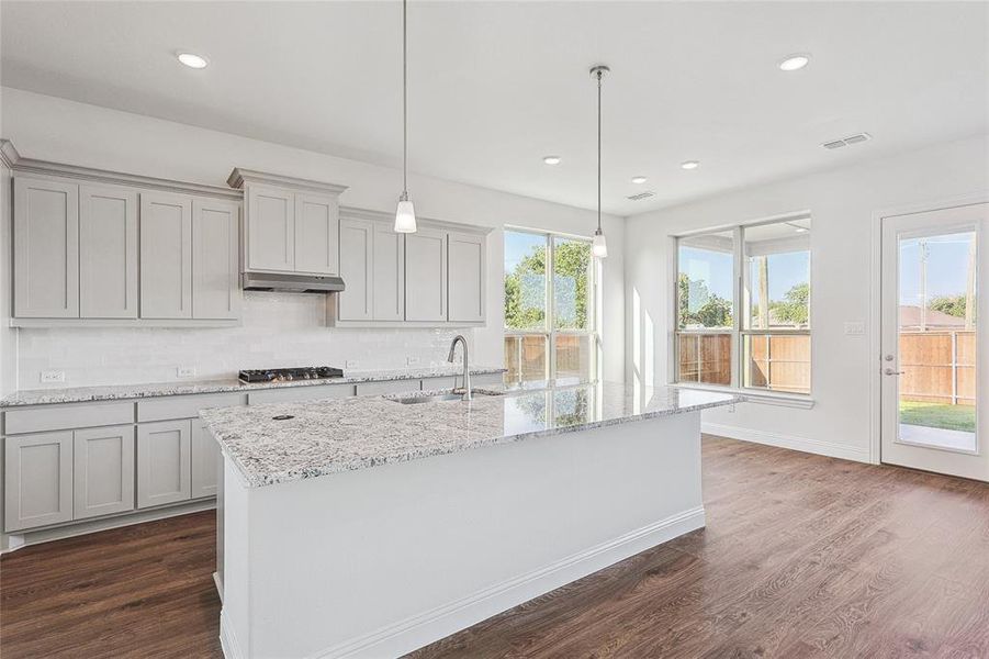 Kitchen with stainless steel gas cooktop, plenty of natural light, sink, and dark hardwood / wood-style floors