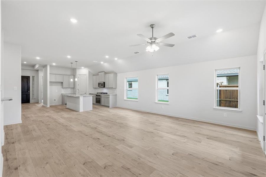 Open-concept living space featuring wood-finish flooring and recessed lighting Open-concept living space featuring wood-finish flooring and recessed lighting