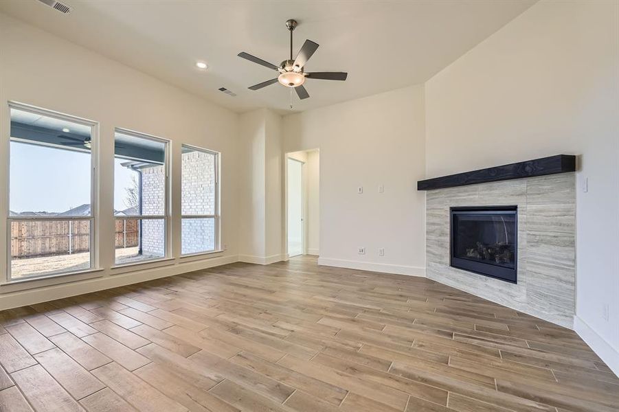 Unfurnished living room featuring baseboards, ceiling fan, recessed lighting, a tile fireplace, and wood finished floors