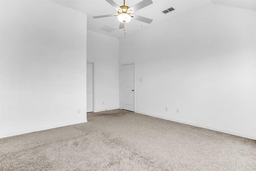 Spacious room featuring vaulted ceilings, a ceiling fan with integrated lighting, and neutral-toned carpeting