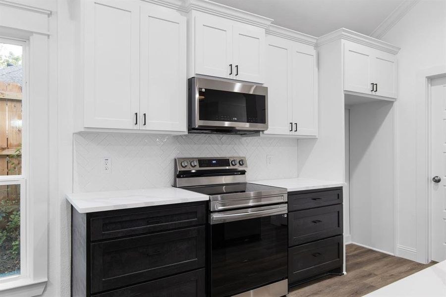 Kitchen with stainless steel appliances, white cabinetry, ornamental molding, backsplash, and dark hardwood / wood-style flooring