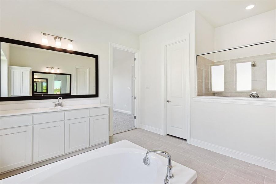 Bathroom featuring tile patterned floors, vanity, and a tub to relax in