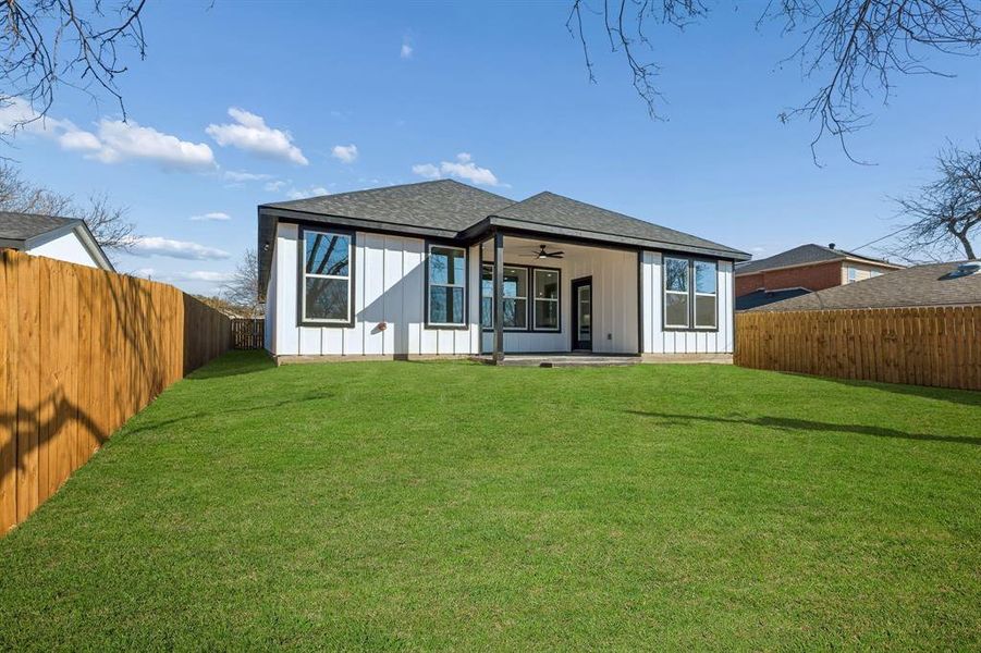 Back of property featuring ceiling fan, a patio area, a fenced backyard, board and batten siding, and a shingled roof