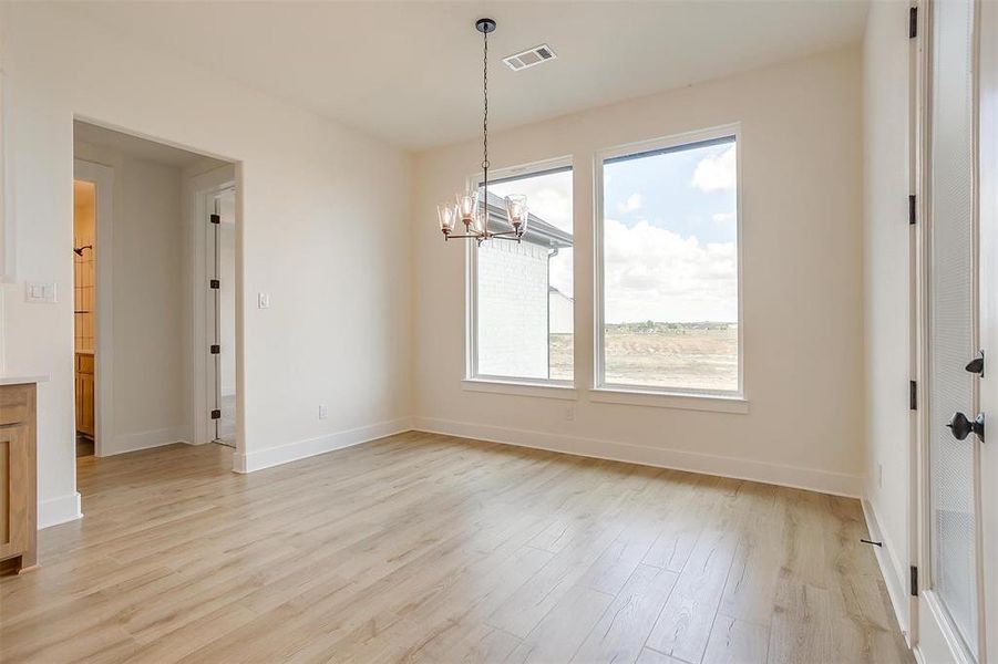 Unfurnished dining area with a notable chandelier and light hardwood / wood-style floors