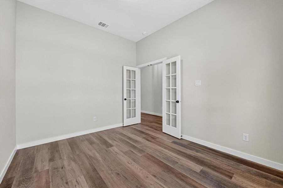 Room featuring wood-finish flooring, light neutral wall paint, and white baseboards Room featuring wood-finish flooring, light neutral wall paint, and white baseboards