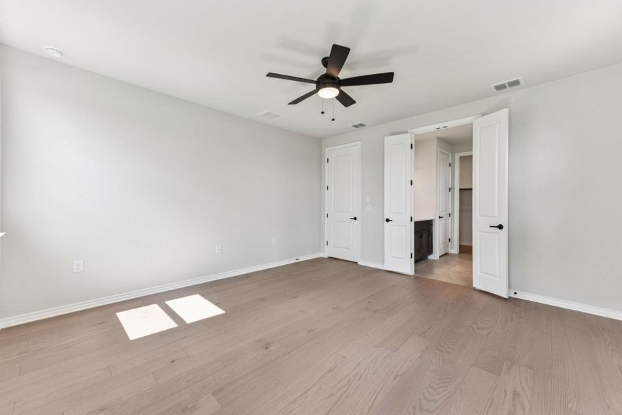 Unfurnished bedroom featuring light wood-style flooring, ceiling fan, and connected bathroom