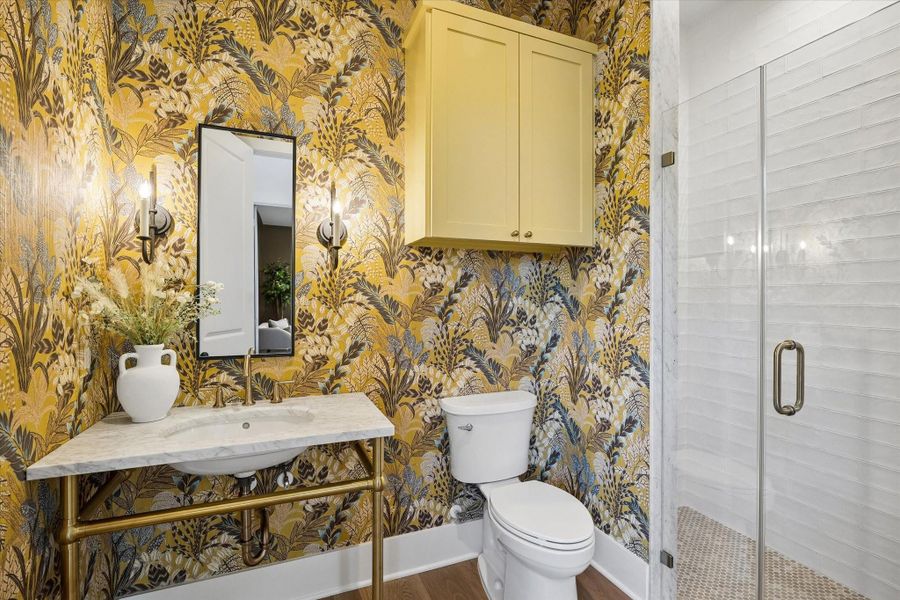 Bold wallpaper and a console vanity wrapped in brass create a powder bath that feels like a designer moment. Framed glass shower with marble trim and penny tile flooring elevates this space well beyond expected for guest quarters.**PREVIOUS BUILDER WORK** Bold wallpaper and a console vanity wrapped in brass create a powder bath that feels like a designer moment. Framed glass shower with marble trim and penny tile flooring elevates this space well beyond expected for guest quarters.**PREVIOUS BUILDER WORK**